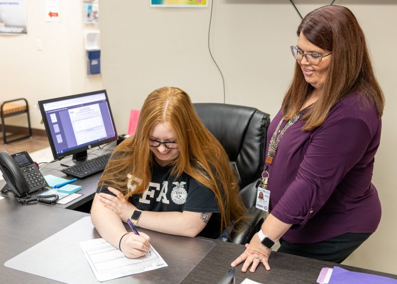 In this photo Seminole State College Director of Enrollment Management Edith Cathey (right) assists Madalyn Douthit (left), of Seminole, as she completes the scholarship application.