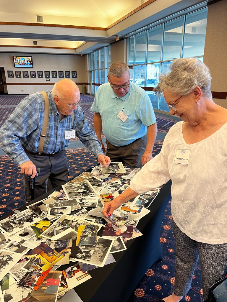 In this photo, retirees Tom Stephens, Dan Factor and Jonna Bunyan peruse a collection of photos from the college’s archive during the luncheon.