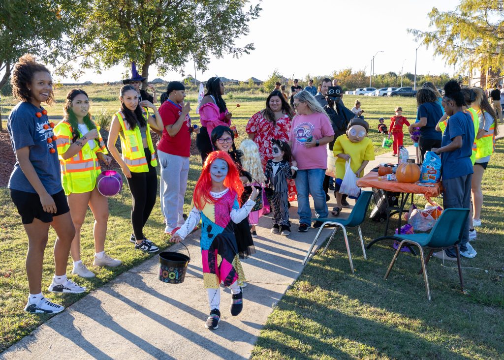 In this photo, children dressed up in Halloween costumes interact with SSC staff and student athletes during Trick or Treat Trail in 2023.