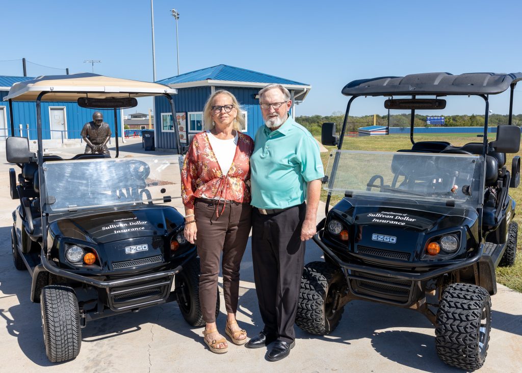 In this photo Trustee and Owner of Sullivan-Dollar Insurance David Wilson (right) and his wife Cindy Wilson pose with the two golf carts they donated.