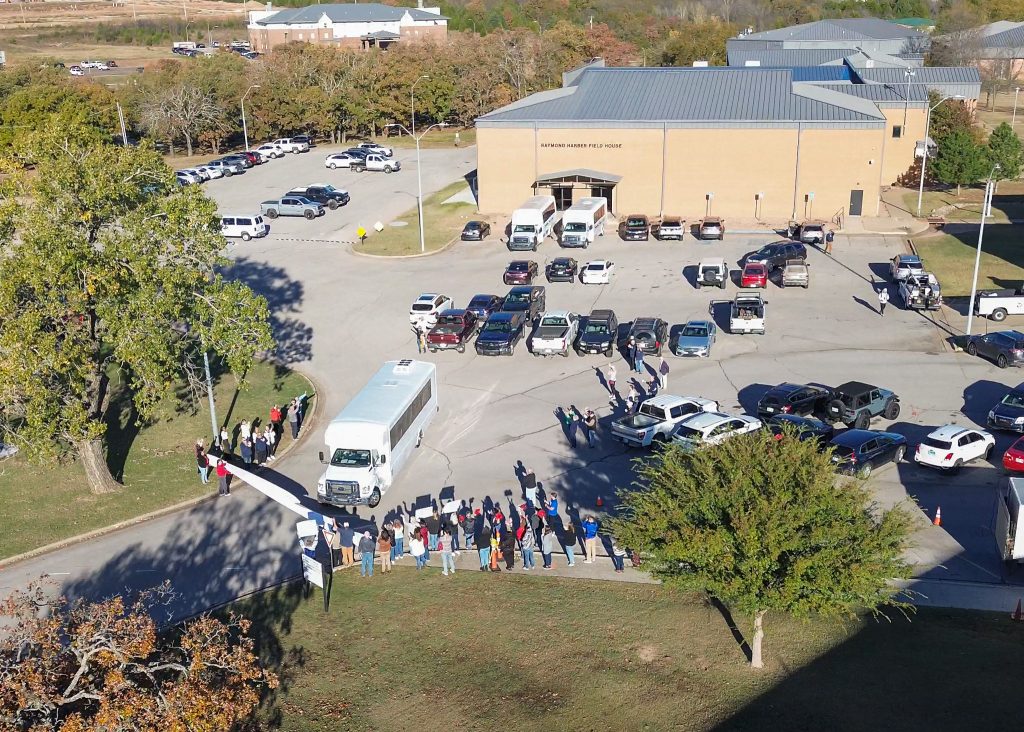 This photo shows an ariel view of SSC soccer fans lined up, holding signs, and cheering as the SSC women's soccer team leaves on a bus for the national tournament. 