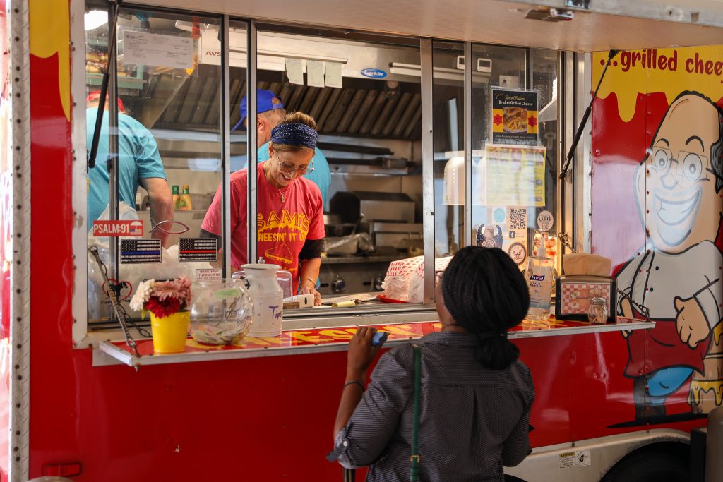 In this photo, an attendee of the event orders food from Veteran owned-and-operated food truck Sam’s Cheesin’ It.