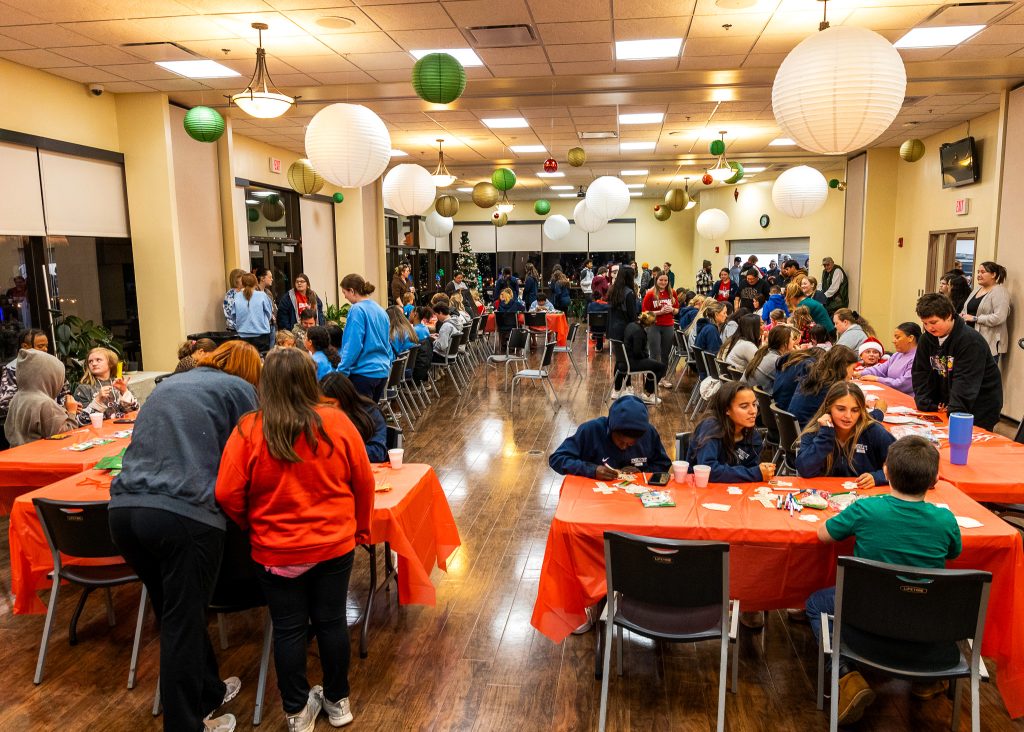 In this photo, local families alongside dozens of SSC student-athletes are busy working at crafting stations, helping community children create crafts.