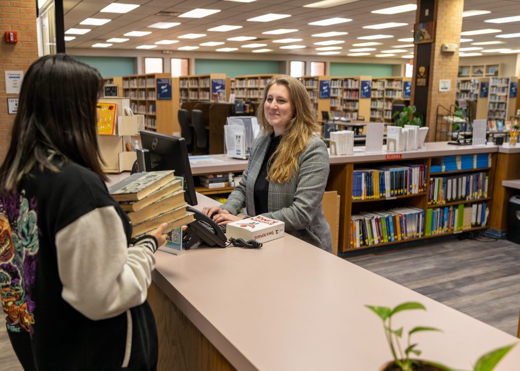 In this photo, Seminole State College Research Librarian, Ashley Bagwell, assists a student with books.