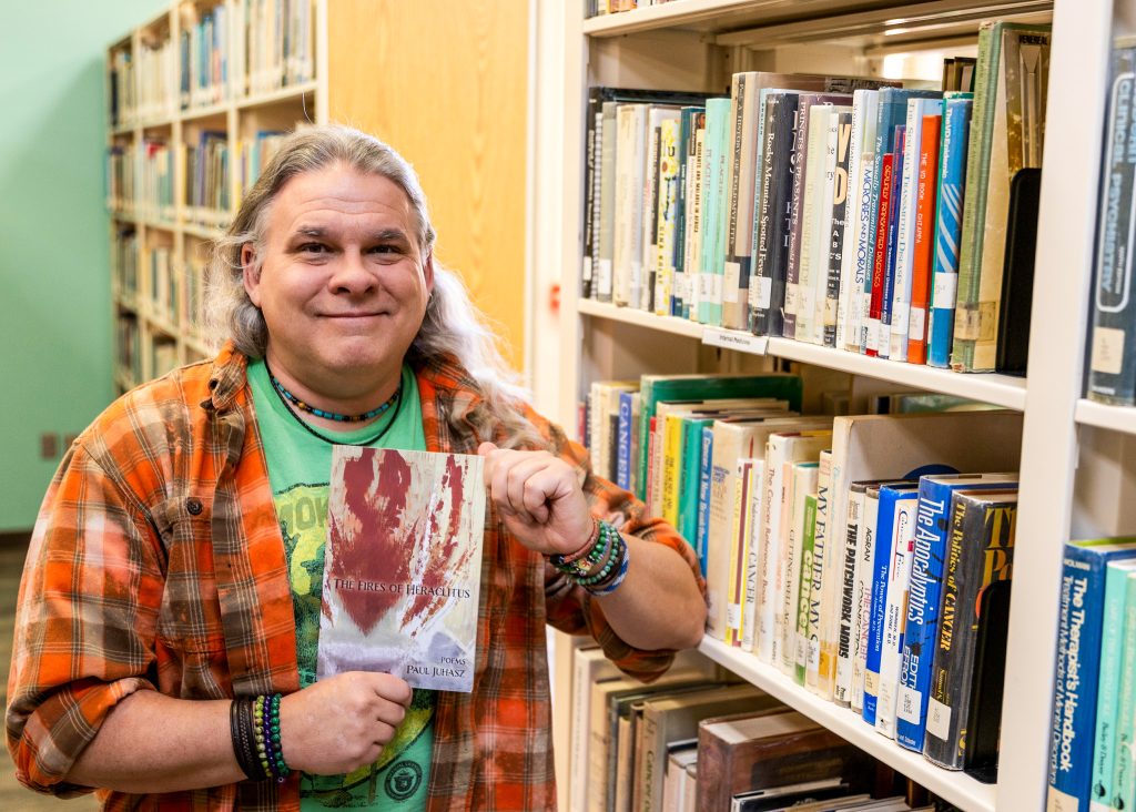 In this photo, Seminole State College Assistant Professor of English Paul Juhasz poses with his most recent work, “The Fires of Heraclitus.”